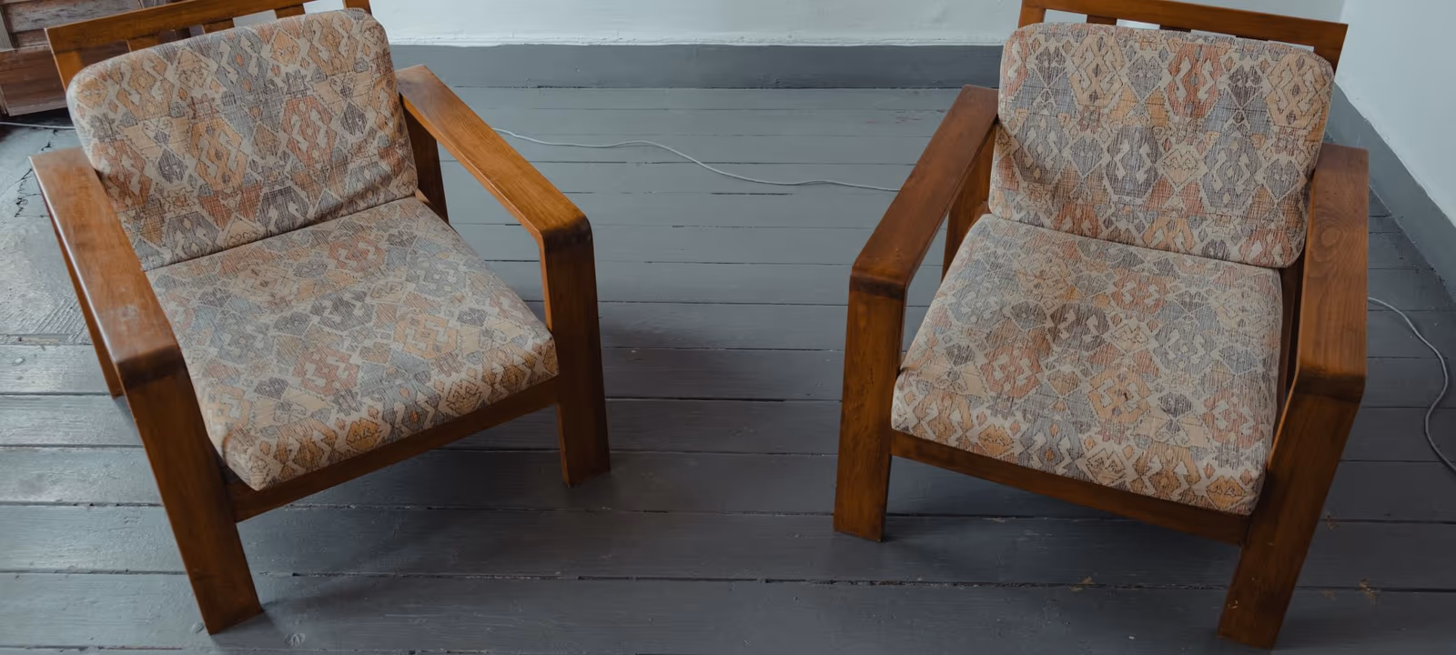 Two chairs facing one another in an otherwise empty room with bare walls