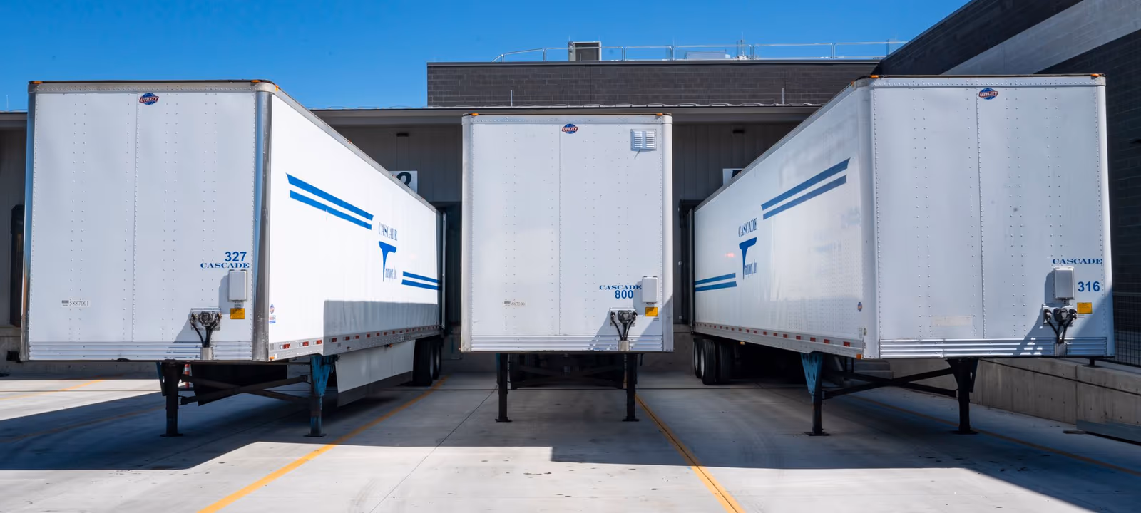 A loading dock seen along its length, roller doors open onto parked trailers