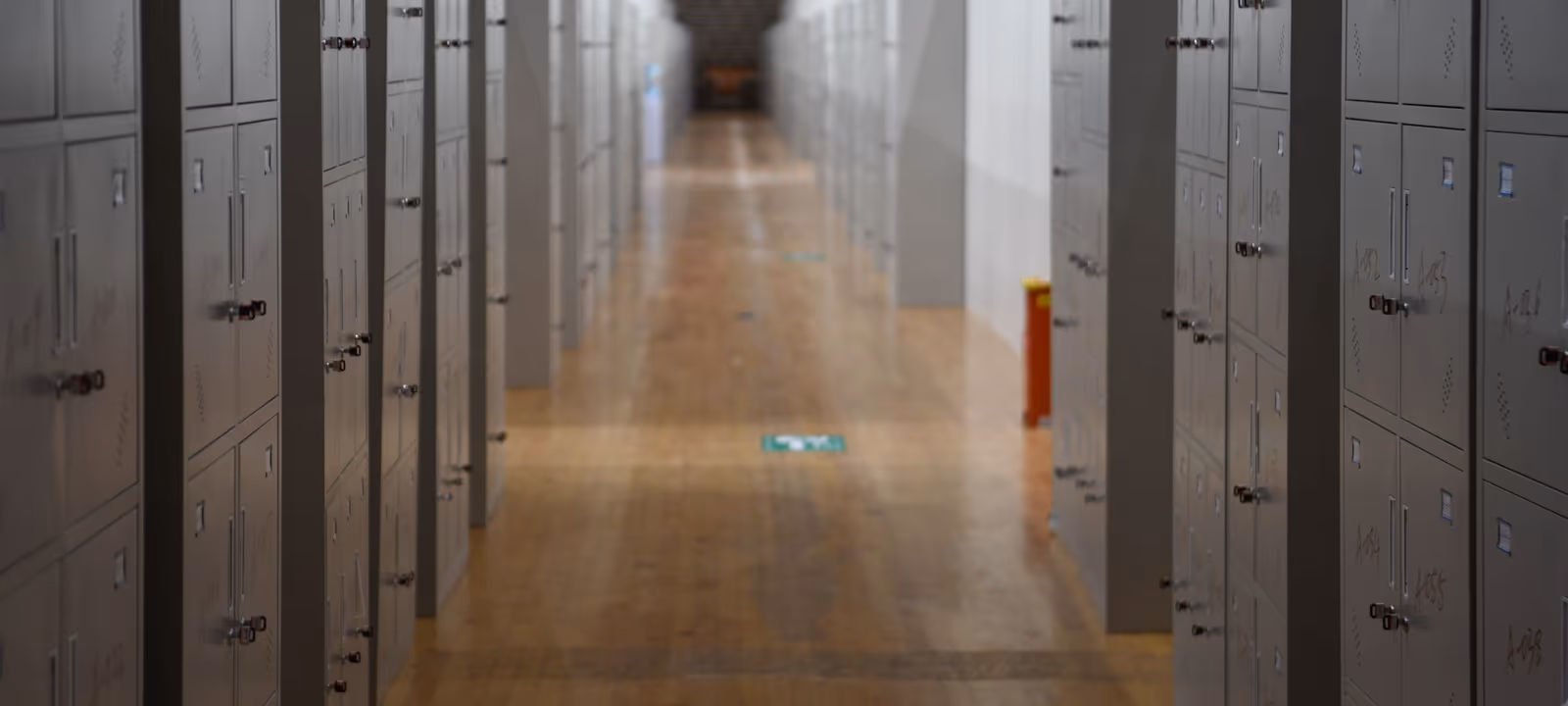 An empty school corridor lined with lockers, floor reflecting overhead light