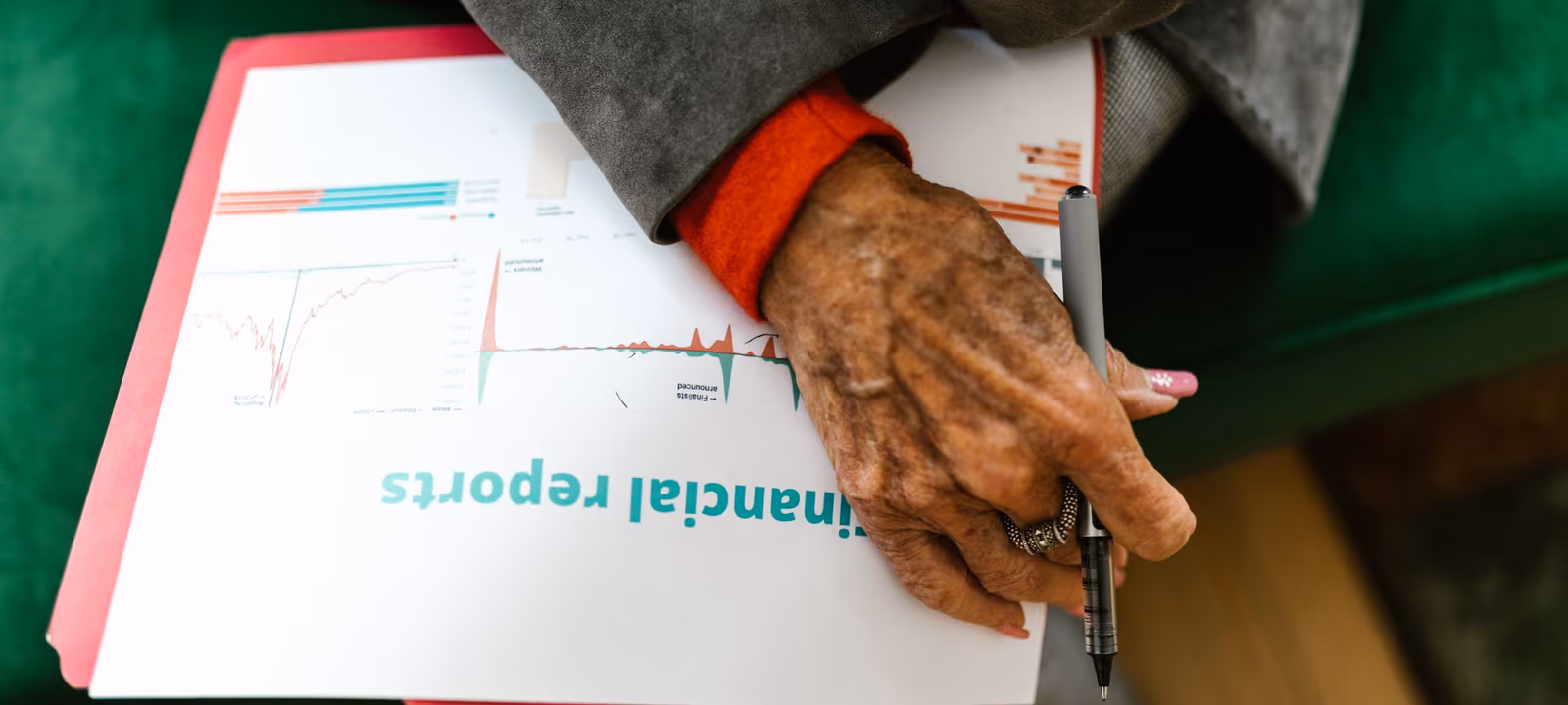 Printed spreadsheets spread across a desk with a pen resting on one page
