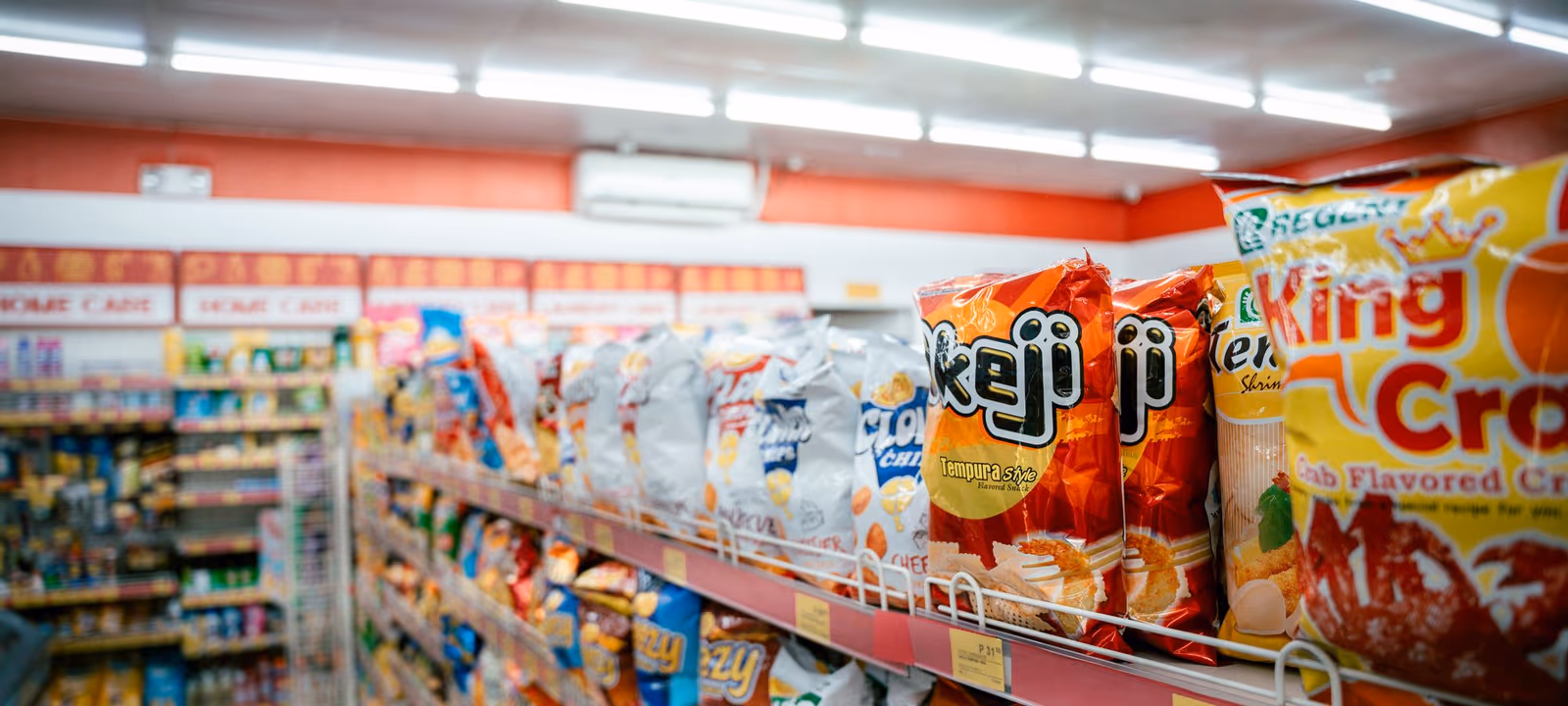 Packaged goods arranged in rows on grocery shelving, receding along the aisle