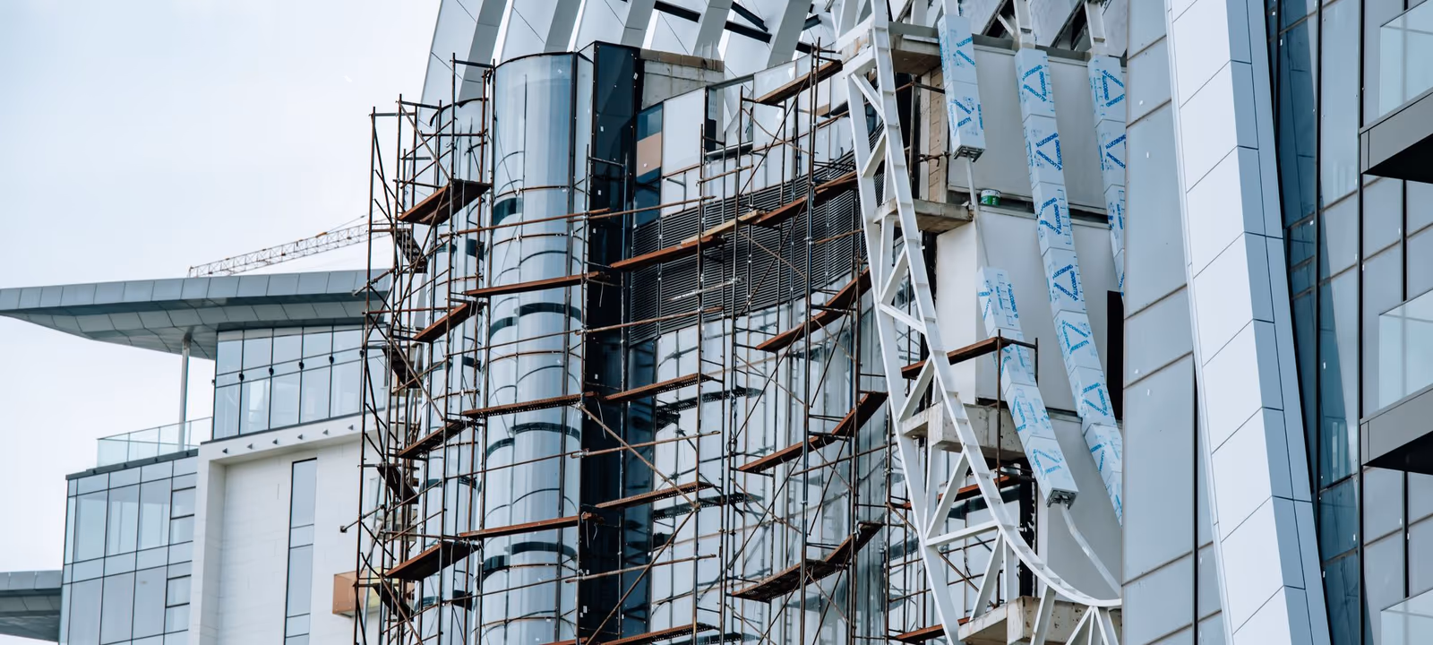 A building under construction with scaffolding across an exposed concrete frame