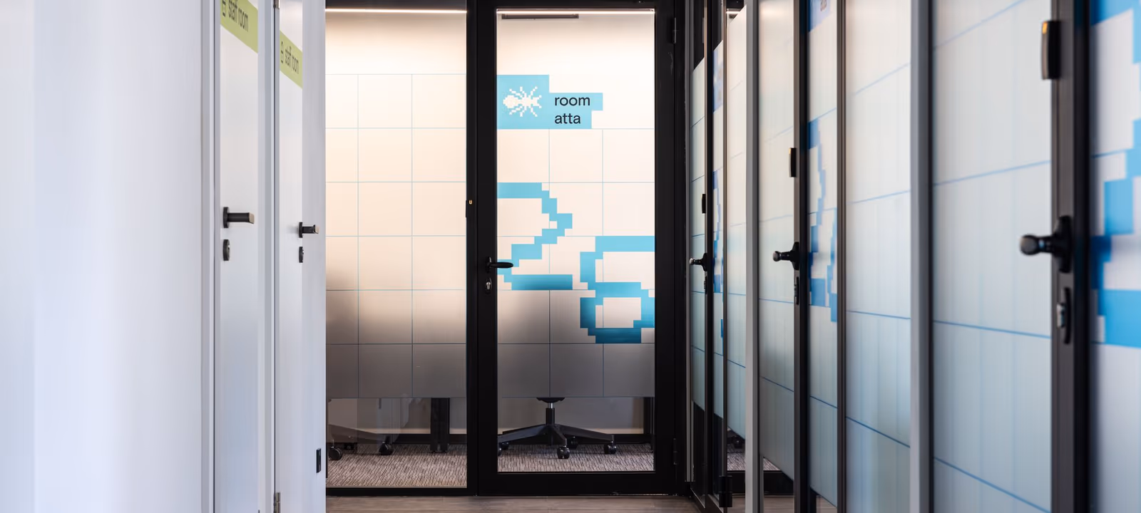An office corridor with meeting room doors along one side, all closed