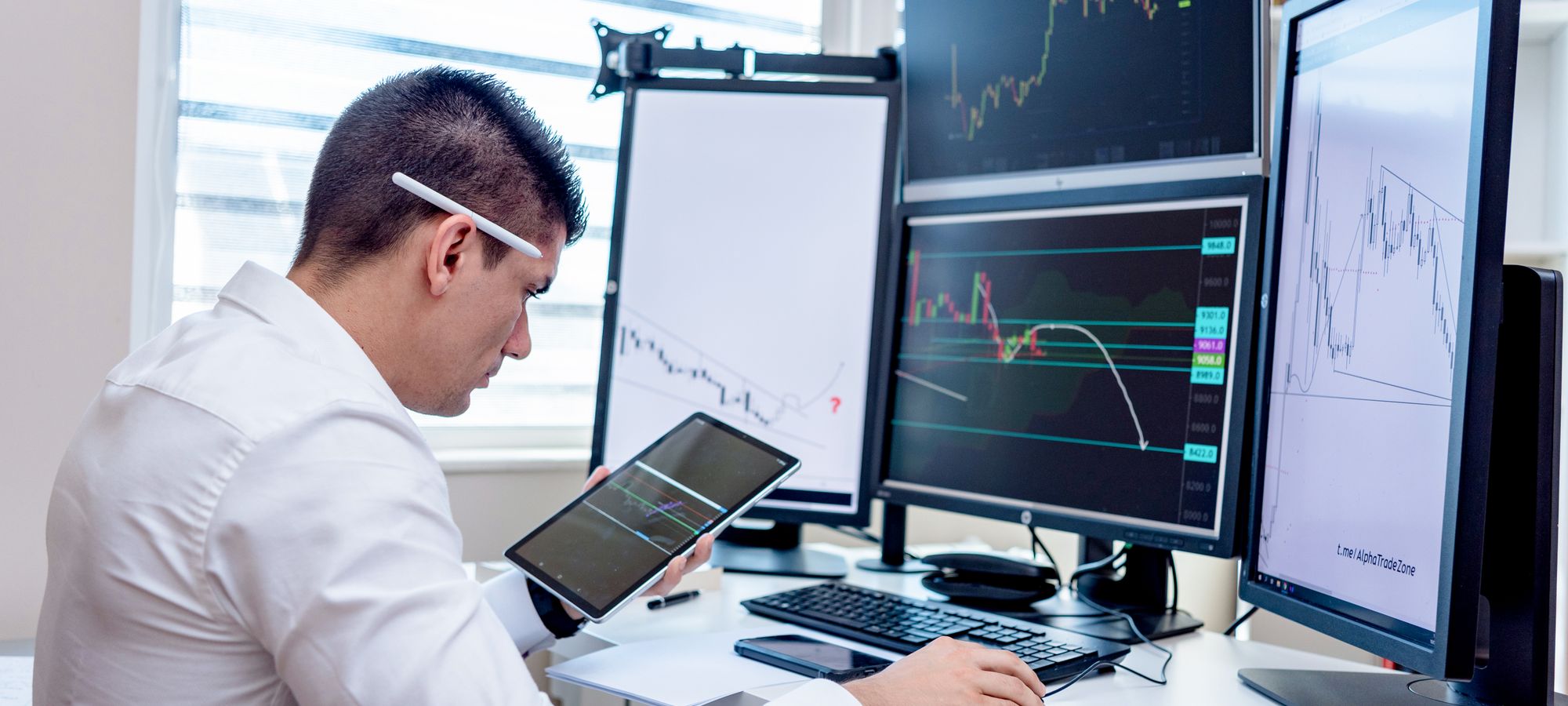 An analyst at a desk with several market screens