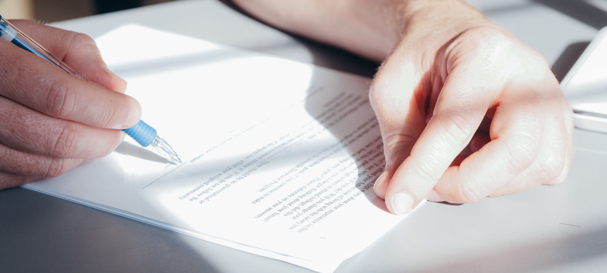 A hand signing a document
