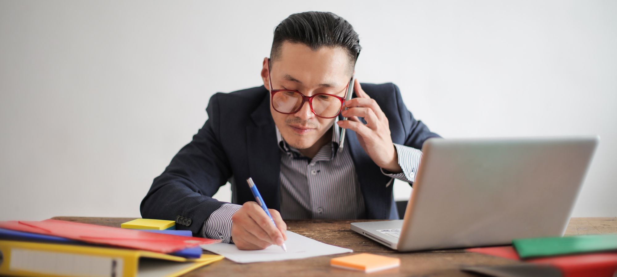 A professional taking notes during a phone call