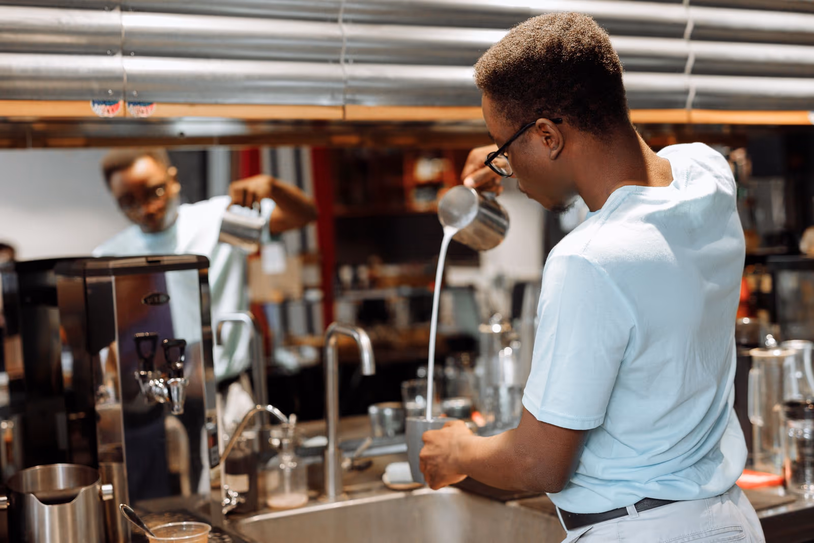 A barista preparing drinks behind a cafe counter