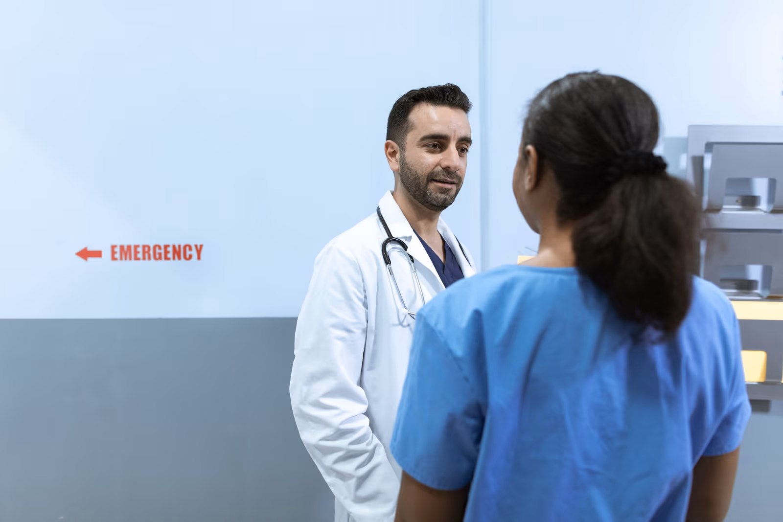 A physician talking with a nurse in a hospital corridor