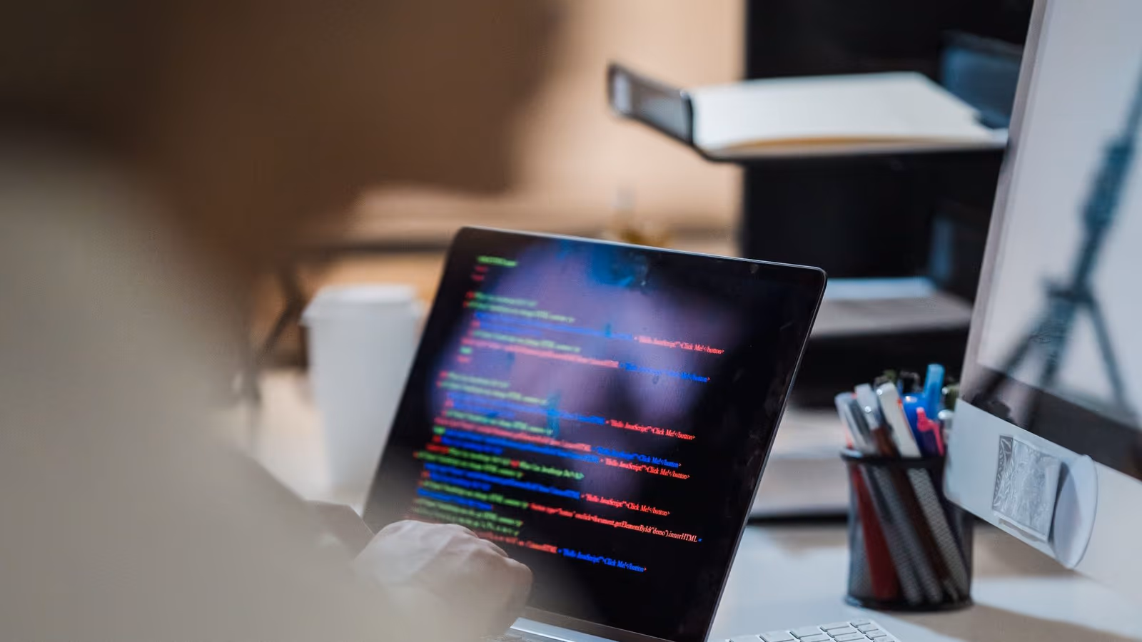 A laptop showing lines of data on a dark desk
