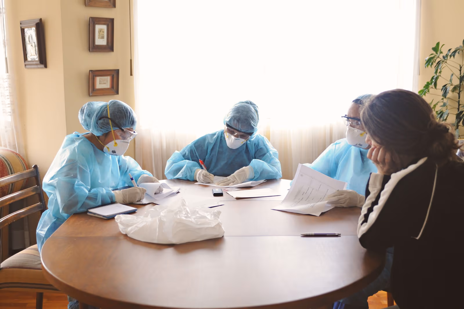 Clinicians in gowns and masks reviewing papers around a meeting table