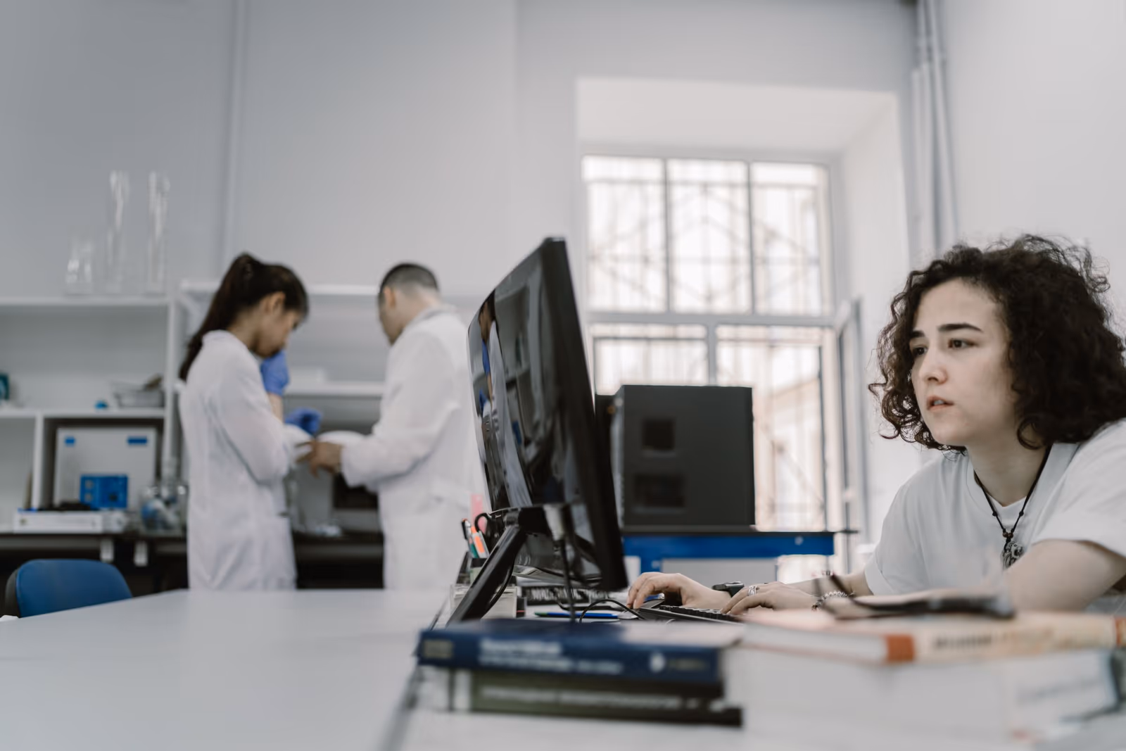 Scientists in white coats working at a laboratory bench and computer