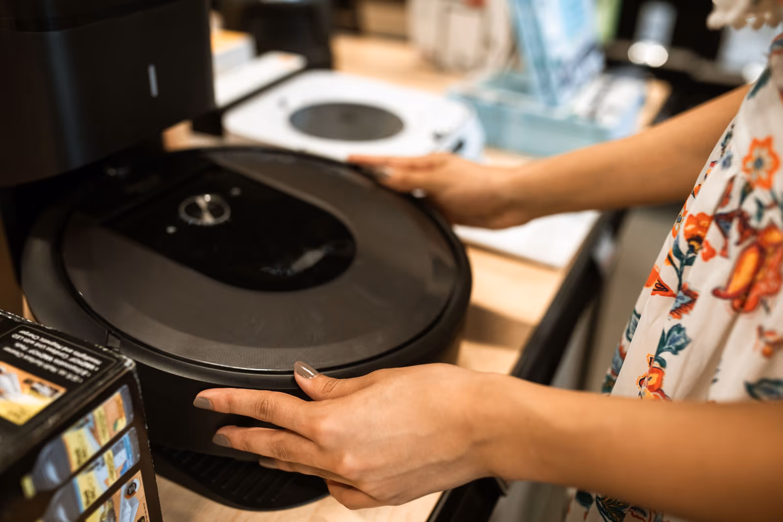 A person handling a round home appliance on a store counter